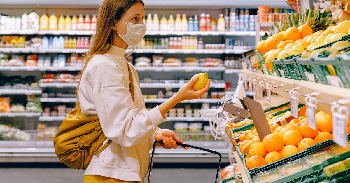 UK Visitors and NHS Health Services - Woman in Yellow Tshirt and Beige jacket Holding a Fruit Stand