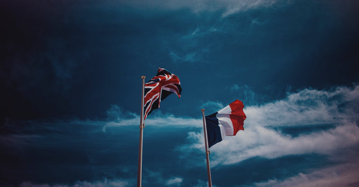 Unique travel destination research methods - Waving flags of France and United Kingdom against blue sky