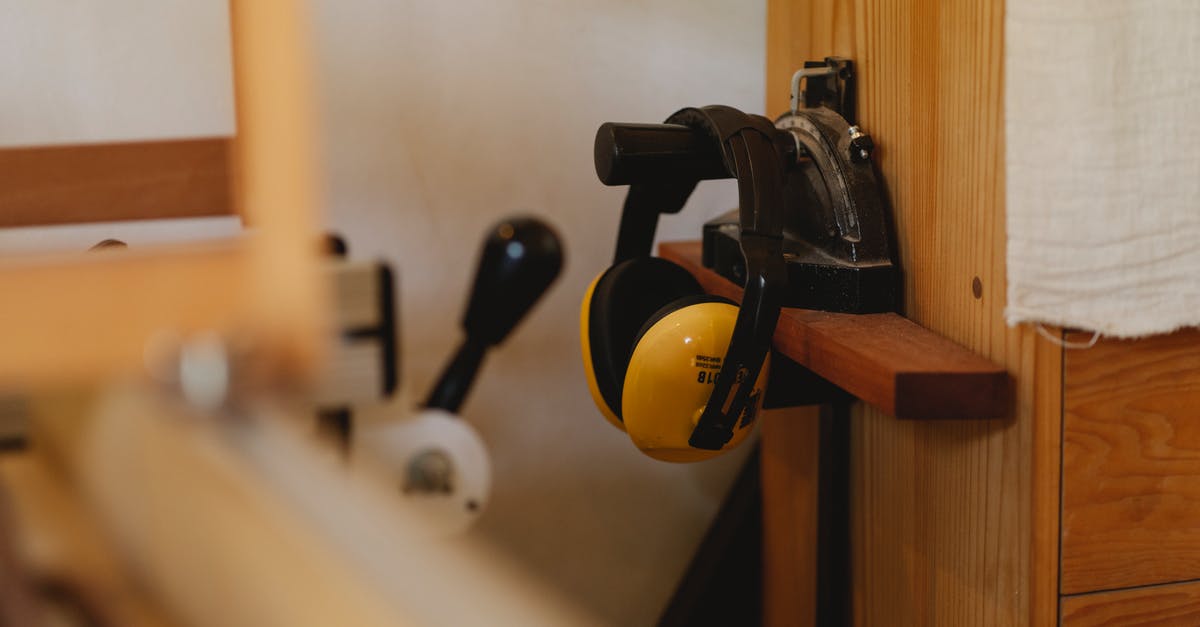 United Airlines domestic travel noise cancelling headphones carry on - Yellow noise cancelling headphones for carpentry work hanging on timber shelf in workshop