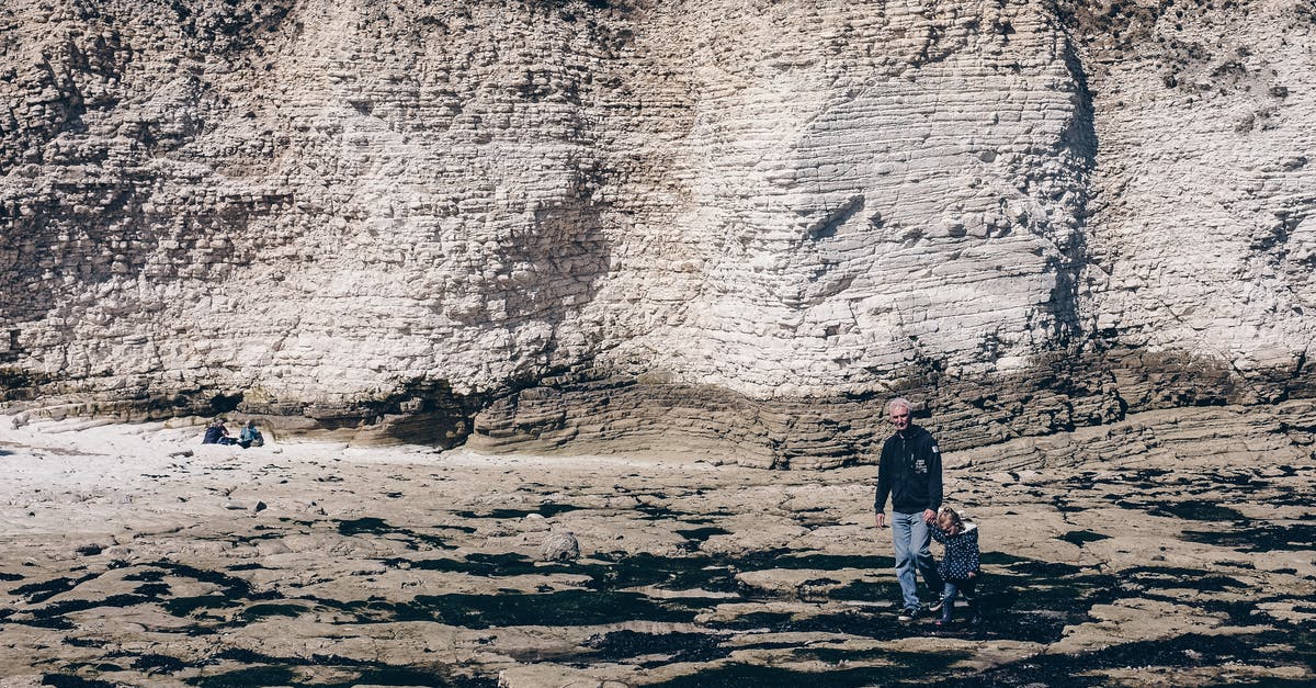 United Kingdom 1 week trip - Anonymous person with kid walking along rocky shore near cliff