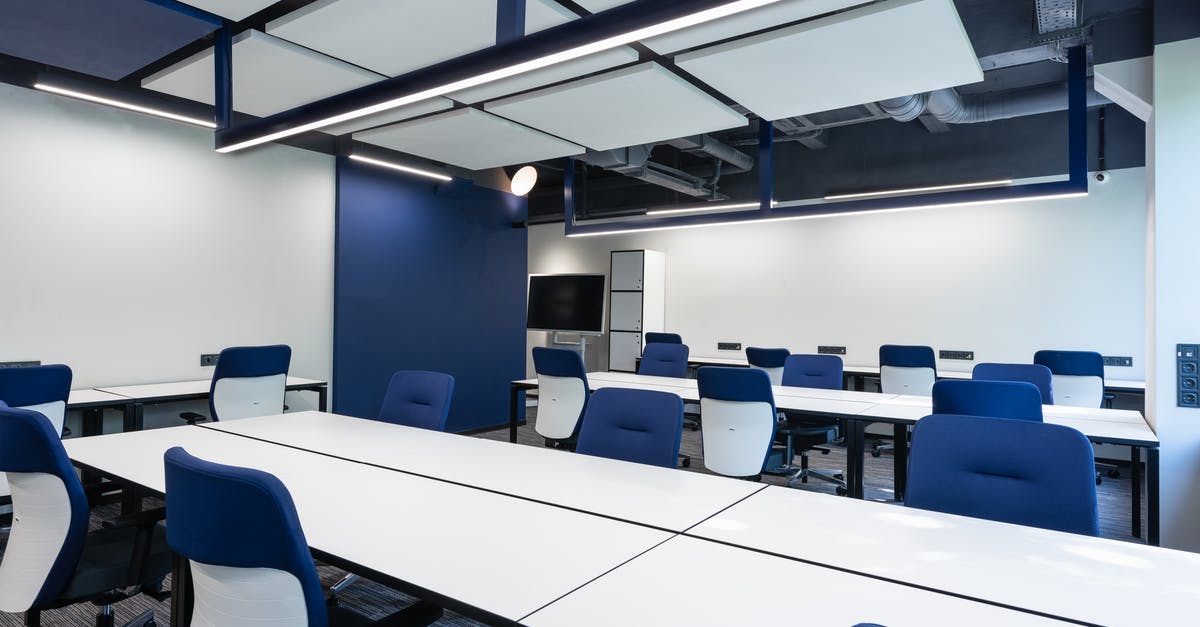 Universities open to public in South Korea and Japan? - Interior of modern spacious workspace with long white tables and blue armchairs placed near monitor with black screen in business center