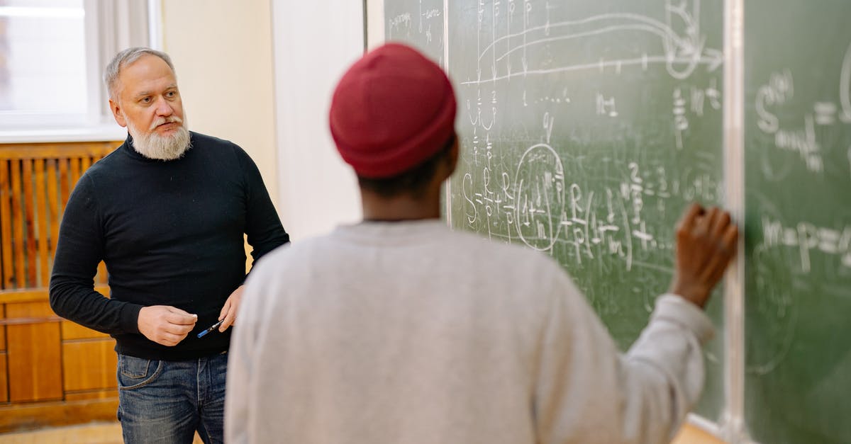 Unused Italian student visa - Man in Black Crew Neck Shirt and Red Cap Standing Beside Man in Gray Sweater