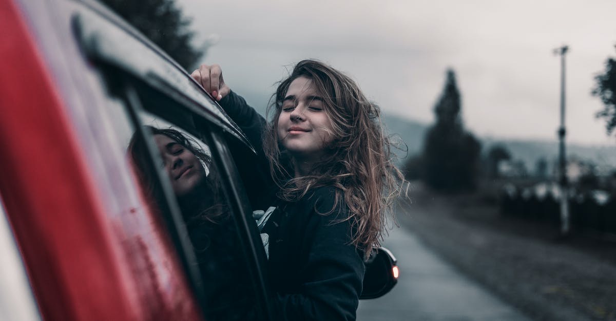 Upper East Side to I-95 South via Car [closed] - Side view of young dreamy ethnic female with closed eyes leaning out automobile window driving on asphalt road near trees and mountains under sky in countryside