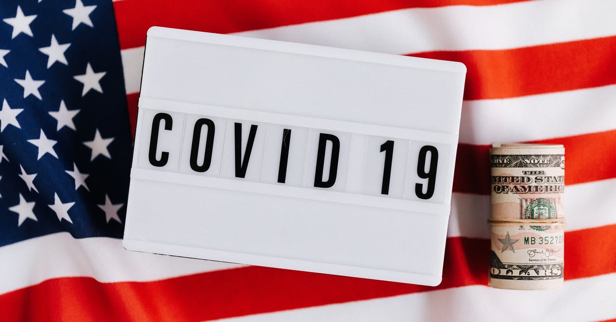 US B1/B2 Visa - regarding number of days of stay - From above of plastic signboard with COVID 19 inscription on flag of USA and roll of paper money during financial crisis