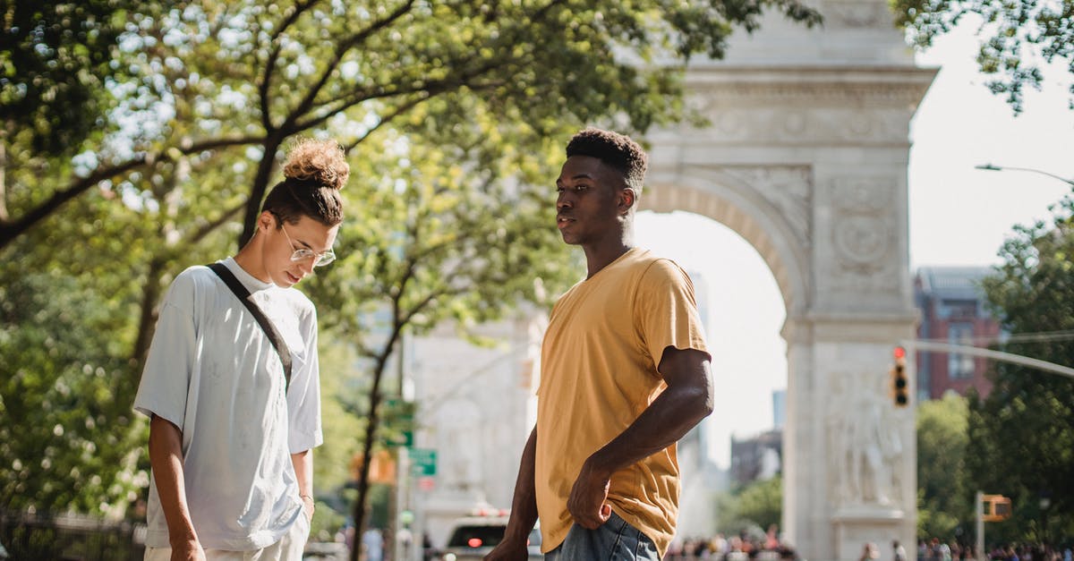 US Preclearance time at Abu Dhabi - (AUH - MAN - ORD) - Stylish young multiethnic male friends in casual clothes standing on street near Washington Square Arch on sunny day in New York