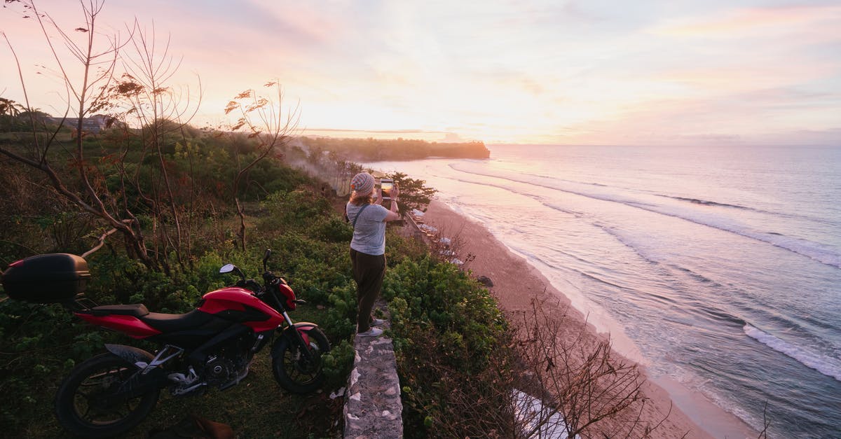 Use bike sharing service as a foreign tourist in China - Woman taking pictures of sunrise on tablet on green seashore