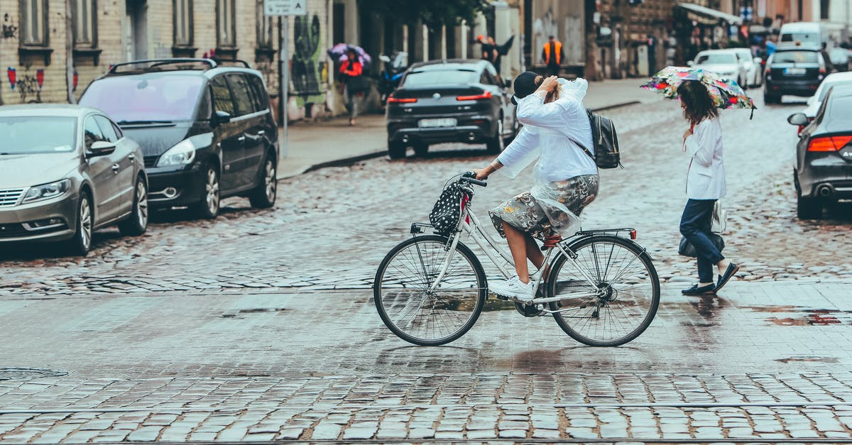 Use cycle path as pedestrian in Netherlands - People protecting from rain while crossing road