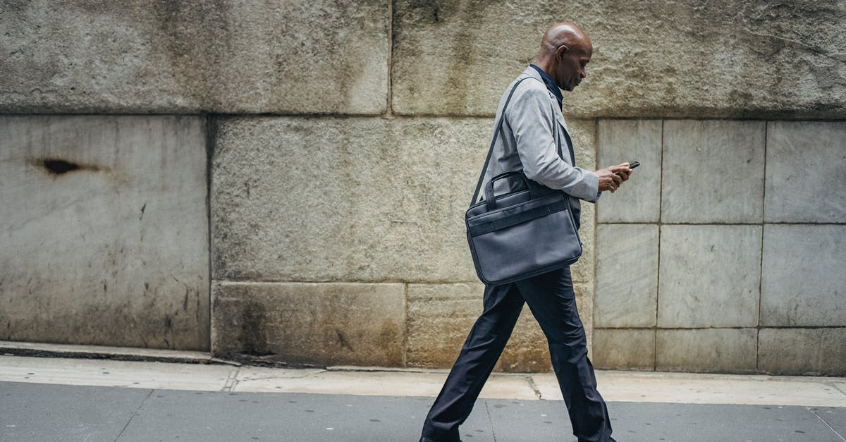 Use cycle path as pedestrian in Netherlands - Busy black manager walking along sidewalk and using smartphone