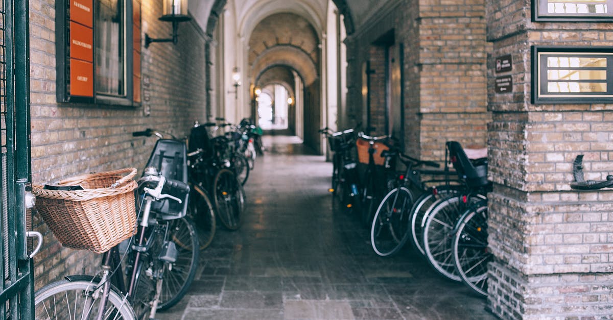 Use public transport with a bike in Japan - Various bicycles parked near brick walls of arched passage on old city street in daytime