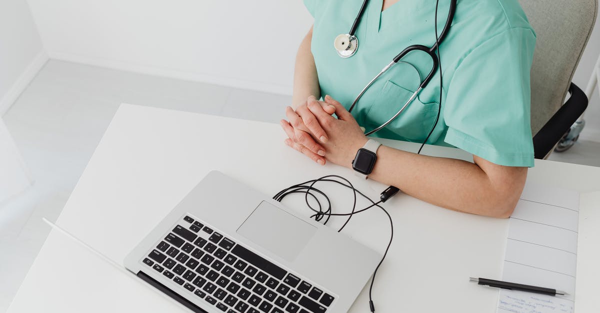 Using 2 Passports - Person in Teal Scrub Suit Using Macbook Pro