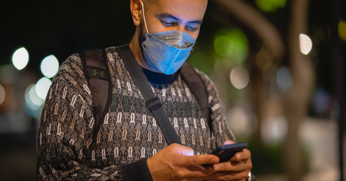 Using a quad-band phone in Japan? - Man with Mask Using a Phone in a Street at Night