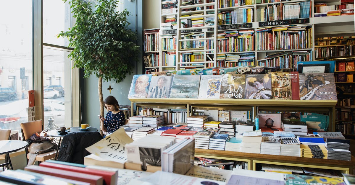 Using different passports in Italy [duplicate] - Young female client in casual wear chatting on cellphone while sitting at table with cup of hot drink in cozy bookstore in afternoon