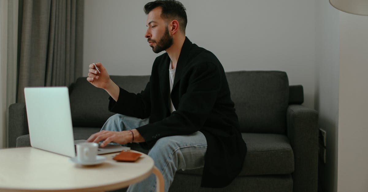 Using LG V10 or Motorola in Japan - Man in Black Blazer and Denim Pants Sitting on a Couch while Using a Laptop