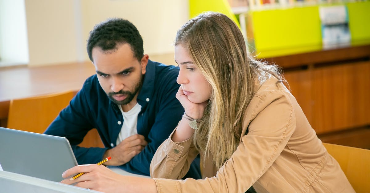 Using library in Frankfurt as a short-term visitor - Concentrated multiracial classmates using laptop for studies while doing homework assignment together in university