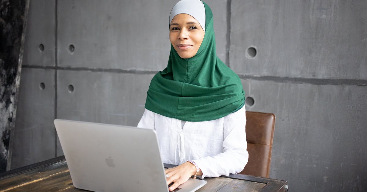 Using Modern Standard Arabic in Arabic-speaking countries - Positive Arab female freelancer using laptop while sitting at table