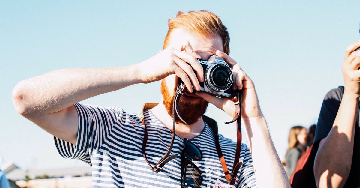 Using old 'full' passport for visa-free travel - Unrecognizable redhead bearded male photographer in casual outfit concentrating on taking picture by vintage photo camera on street event at daytime