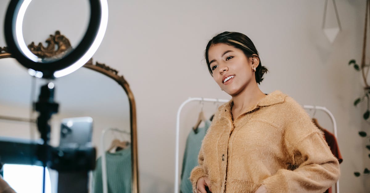 Using restroom on airplane while fasten seatbelt light is on? - Low angle of positive ethnic female blogger shooting video on cellphone on tripod with shining lamp