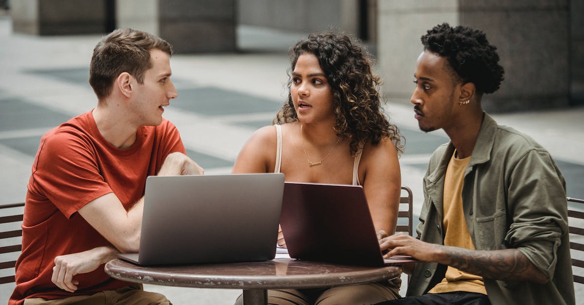 Using status across other Star Alliance airlines? - Focused young multiethnic colleagues sitting at round table with laptops and discussing project details in city