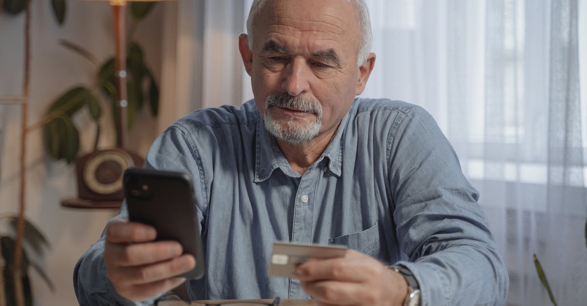 Uzbekistan ATMs and Mastercard - An Elderly Man Holding His Mobile Phone and a Credit Card