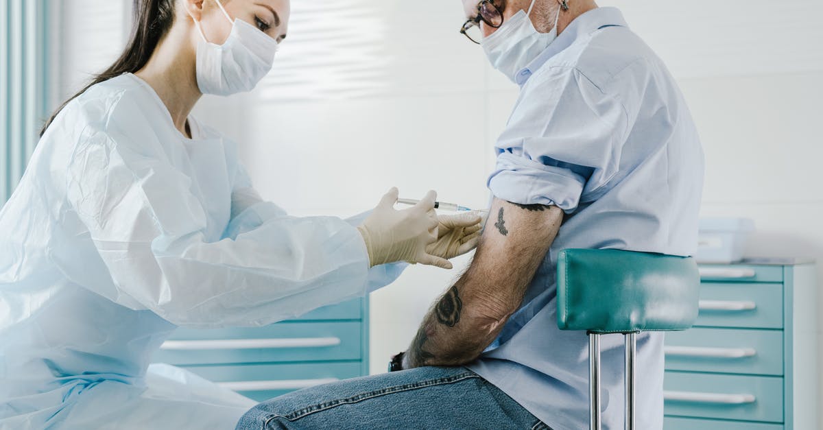 Vaccine certificate conditions for Armenia entrance - Man in Blue Scrub Suit Sitting on Chair