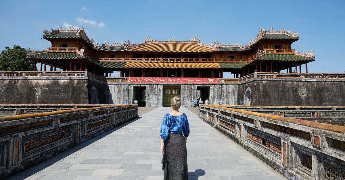 Valid Vietnam tourist visa in old passport - Full body back view of anonymous female traveler strolling on paved walkway near South Gate in Imperial City in Hue