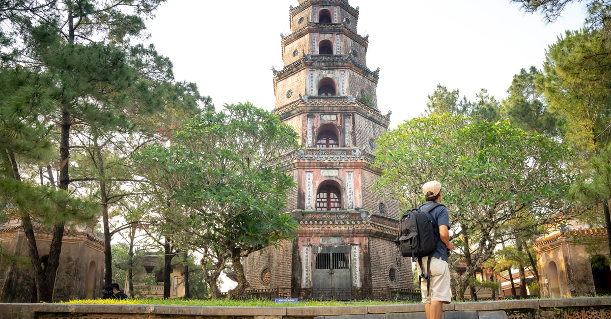 Valid Vietnam tourist visa in old passport - Unrecognizable male tourist walking in park and sightseeing old pagoda