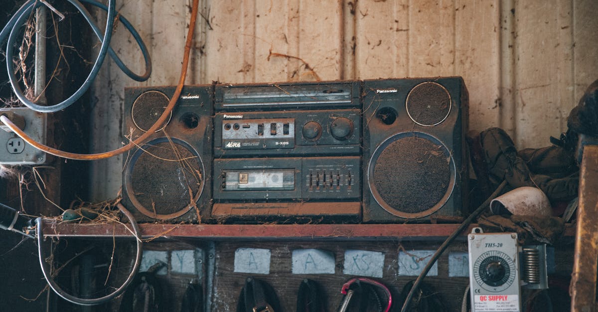 VAT Refund on Used Musical Instruments - Old fashioned obsolete compact stereo system covered with dust placed on shelf near wooden wall in workshop with tools and wires