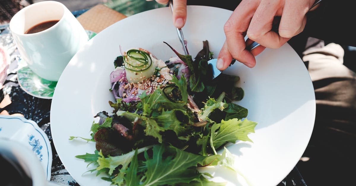 Vegan dining options on Maui - High angle crop anonymous male with cutlery eating tasty mix leaves salads in outdoor restaurant on sunny weather