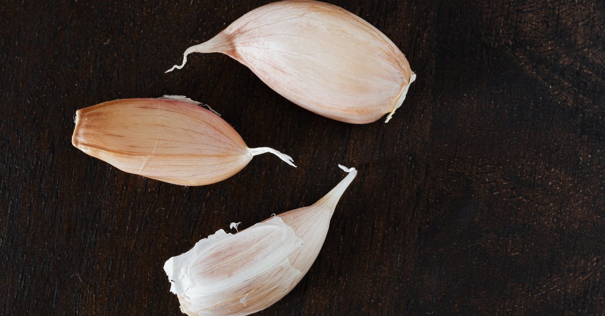 Vegan restaurants in Paris (5th arrondissement) - Top view of several cloves of ripe garlic in peel placed on wooden desk during cooking process at home