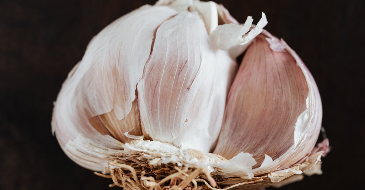 Vegetarian dishes on Russian trains (European part) - Top view of fresh halved garlic in peel placed on dark brown surface before training in restaurant