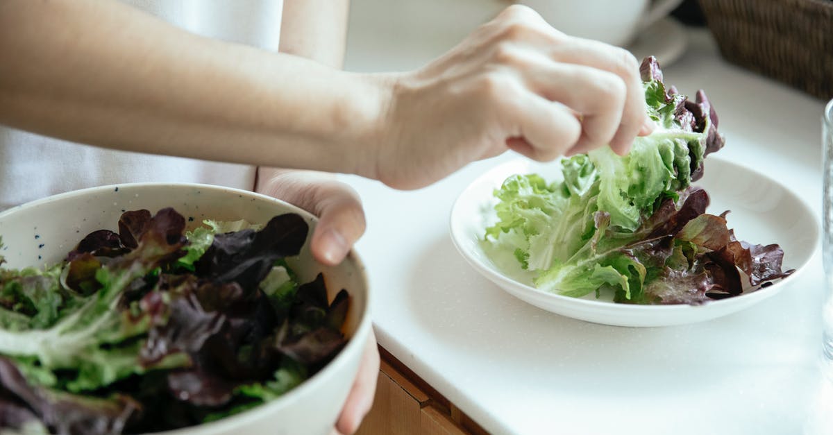 Vegetarian dishes on Russian trains (European part) - From above of crop person putting fresh mix of green salad leaves from bowl into white plate