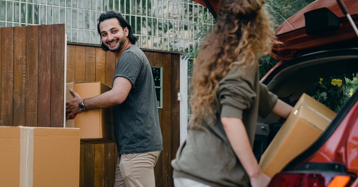 Vehicle Permit at the Mexican Border without owner present - Cheerful modern male and female in comfortable casual clothes unpacking car trunk in green garden of new house while moving in together