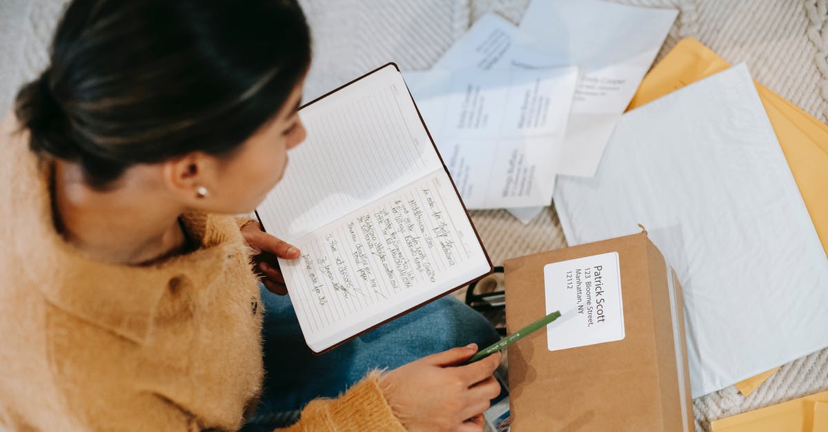 Vfs shipping label not received [closed] - From above concentrated young female checking address details on parcel label while sitting on floor with opened diary