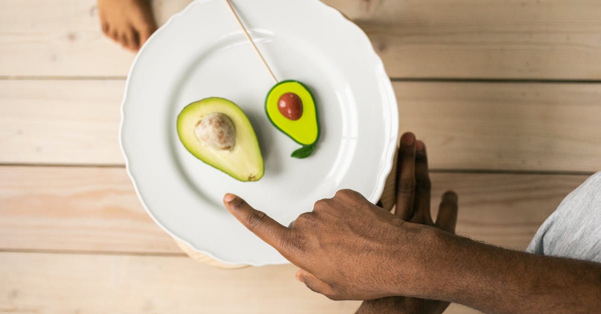 Vietnam e-visa: exit Point differing from entry Point - Top view of crop anonymous African American man pointing on organic healthy avocado helping child to choose between natural fruit and sweet lollipop