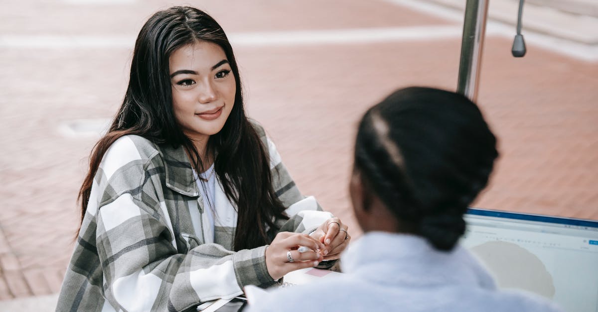 Visa Italy Student or Business from other country - From above of cheerful young diverse female students sitting at table in campus while working on assignment with laptop and tablet and looking at each other