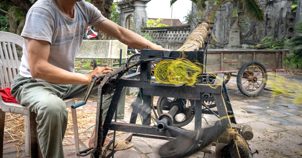 Visa processing speed: VFS vs Embassy - Crop Asian worker cutting tobacco roll on press machine