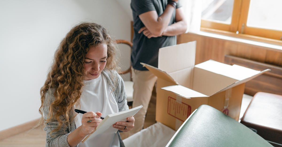 Visa requirements for check out and in - Pensive couple taking notes in bedroom near window while packing stuff in carton box to move into new apartment