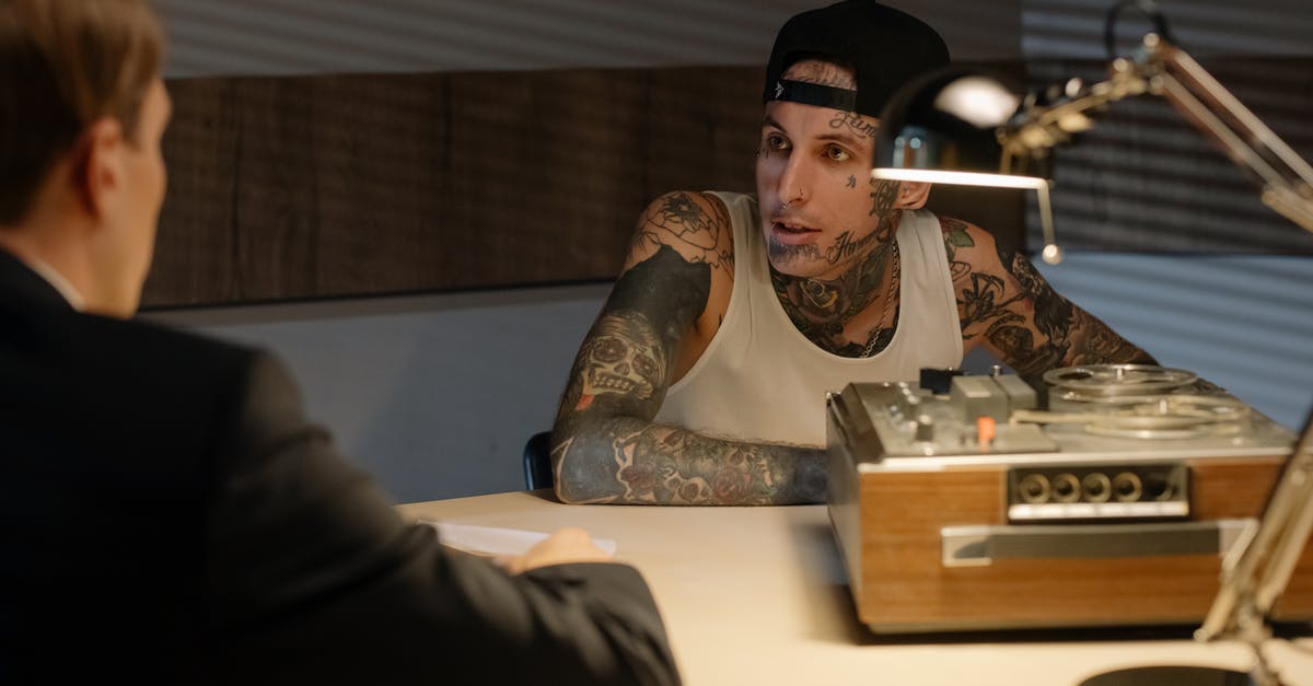 Visa with criminal record - A Man with Tattoo Talking to a Person in a Suit