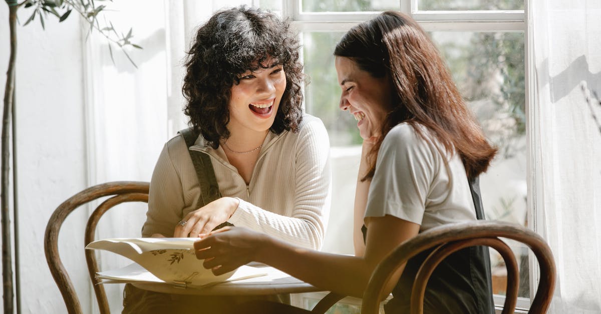 Visit to UK to meet business associate as well as friend - Laughing multiracial female colleagues wearing uniform flipping pages of papers while discussing work together