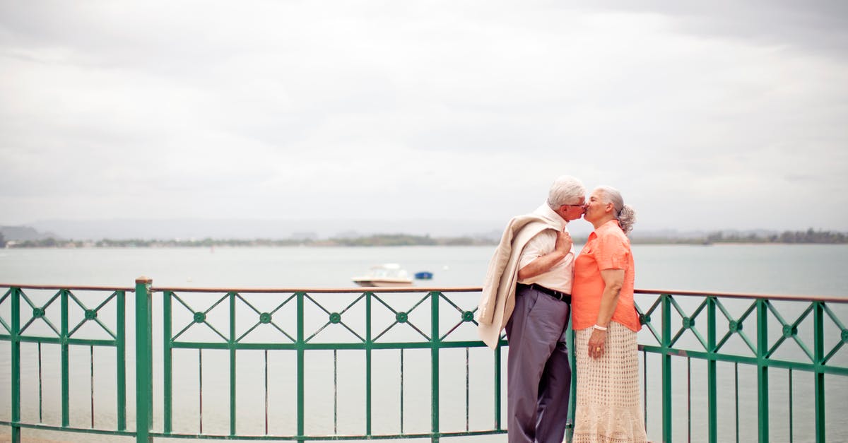 Visit visa for husband [closed] - Side view full body romantic senior couple wearing trendy outfits standing on waterfront promenade and kissing gently on overcast weather