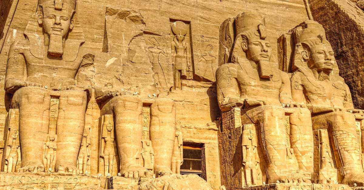 Visiting Abu Simbel in Egypt for independent travellers - Sculptures of ancient Egyptian Pharaoh carved out of rock with decorative elements representing faces and clothes in sanctuary in Egypt