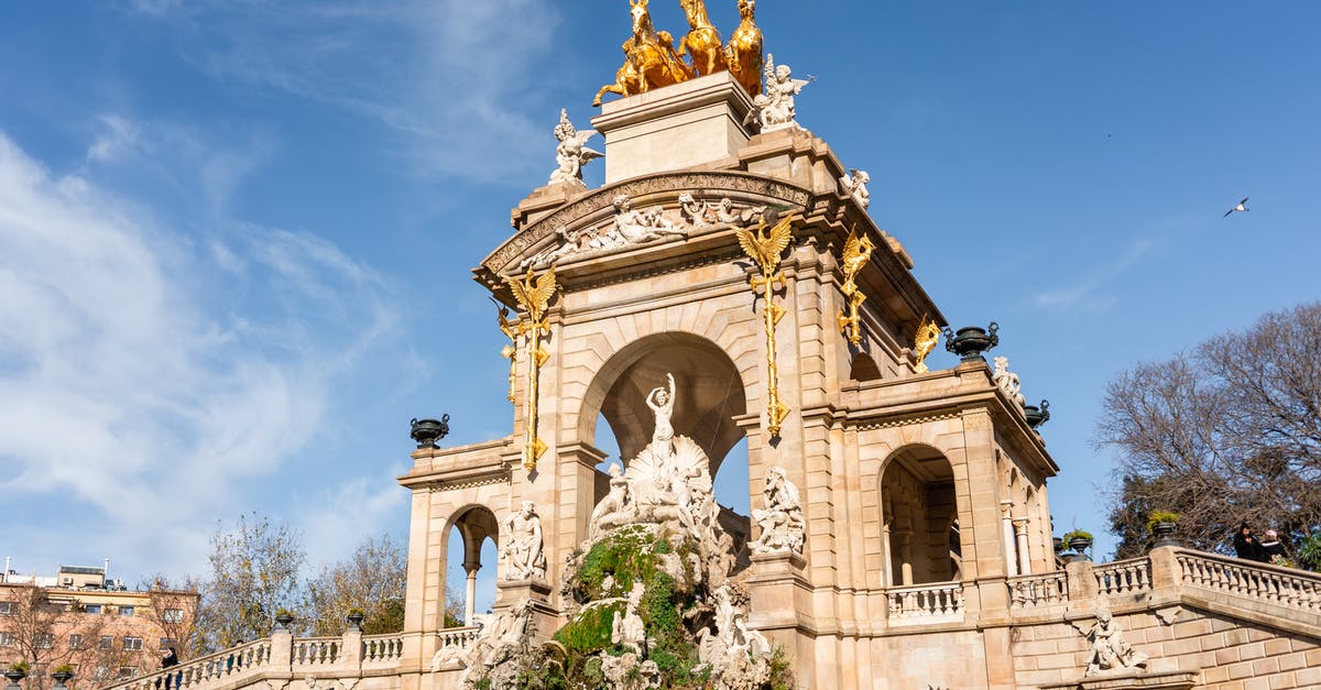 Visiting Andorra from Barcelona - Low angle of aged historic construction with columns and arched entrances decorated with sculptural ensemble with quadriga of Aurora in Citadel Park