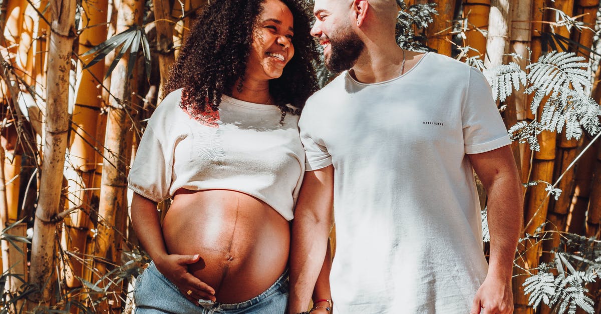 Visiting countries during pregnancy - Happy Couple Expecting for Baby Posing on Bamboo Background