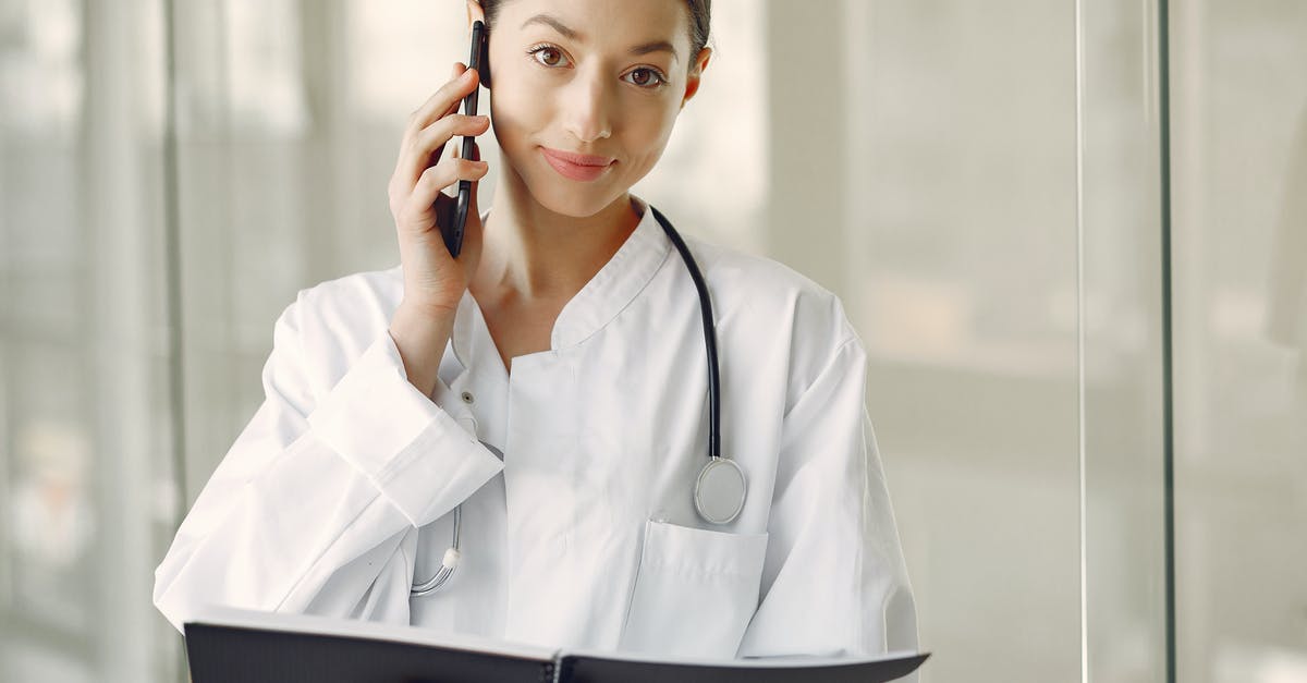 Visiting Derry/Londonderry. What should I call it? - Positive doctor in medical uniform talking on cellphone in clinic corridor