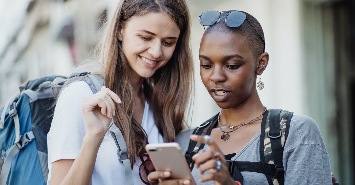 Visiting friends while in transit - Women Travelers Visiting City with Backpacks Using Smart Phone