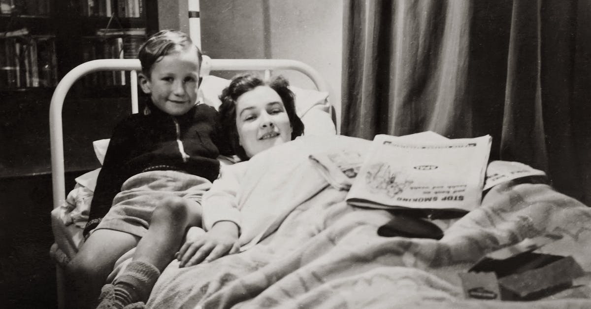 Visiting my mother in the US; she has overstayed her visa - Grayscale Photo of A Boy Sitting Beside His Mother Lying On A Hospital Bed