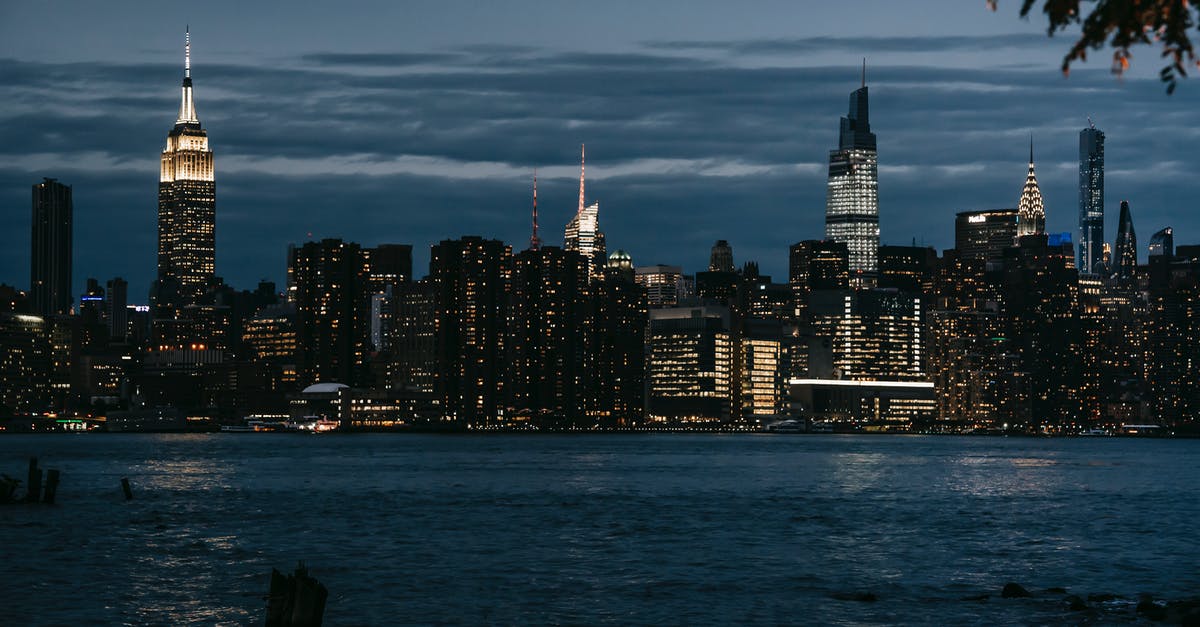 Visiting the housing projects in New York City? - Contemporary illuminated towers located in central district on coast of rippling river in New York at night