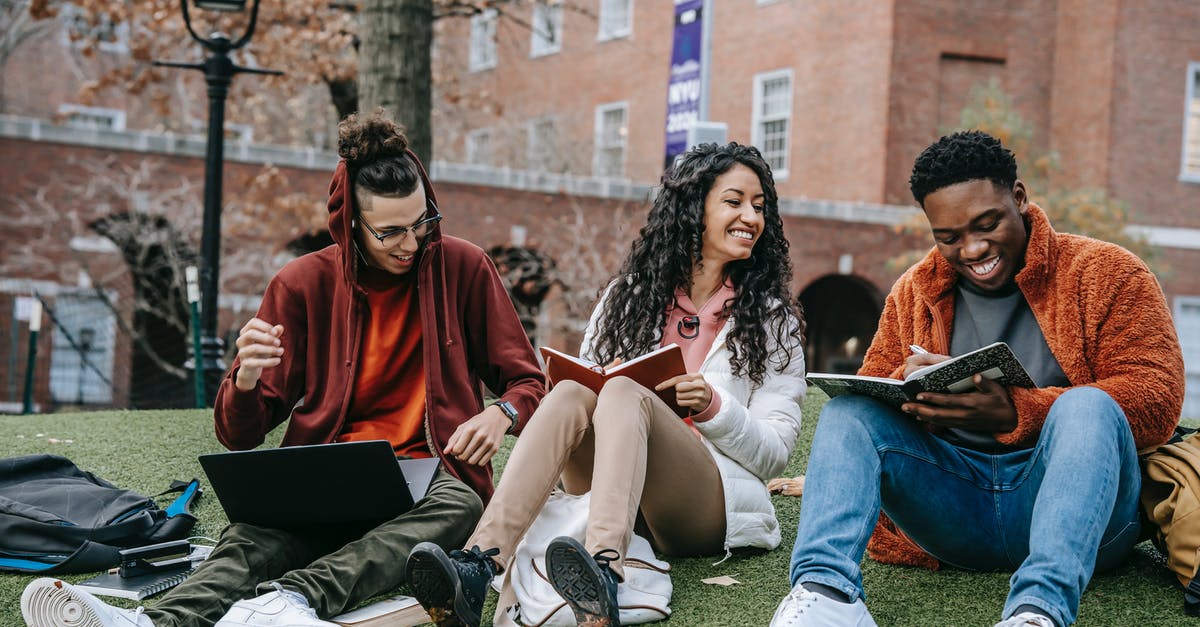 Visitor visa refusal for student friend - Full body of happy diverse students with notebooks and laptop sitting on grassy lawn on campus of university while studying together