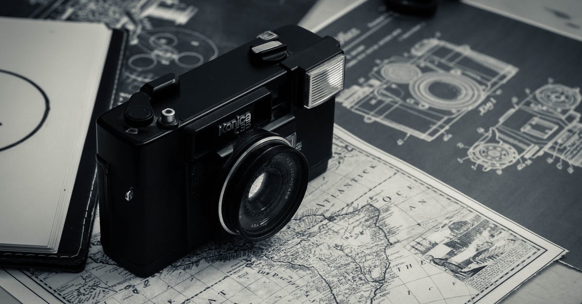 Visualizing Instagram Travel photo locations on a Map - From above of black and white vintage film camera laced on table with map and notebook