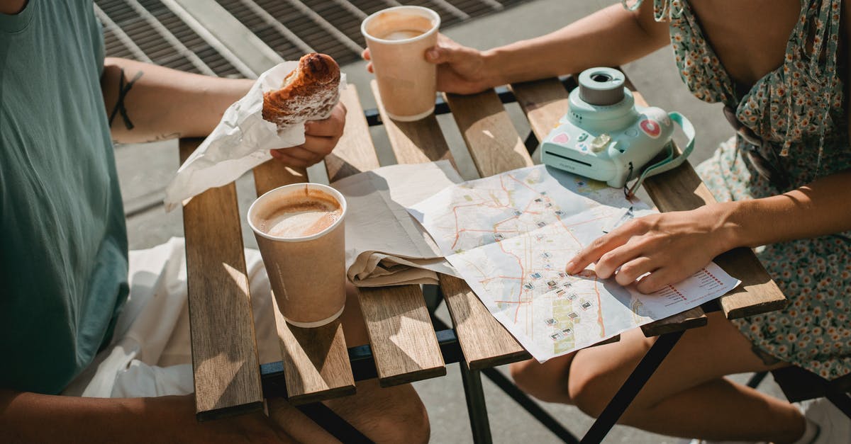 Visualizing Instagram Travel photo locations on a Map - From above of crop anonymous couple searching route in map while having coffee and croissant